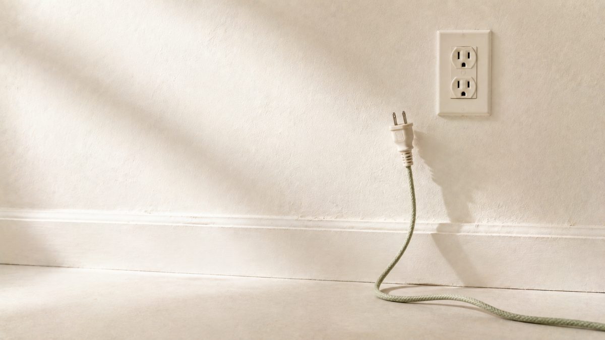 コンセントから抜かれてだらりと垂れた布巻きコードの電源プラグ — 眠れない原因を切り離すイメージ